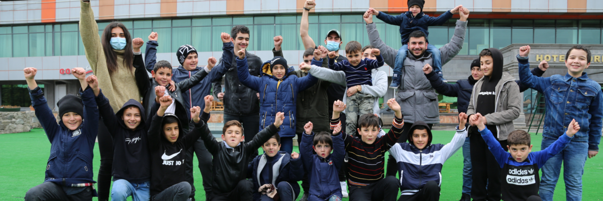 ACT participants playing soccer with children and posing with their hands up