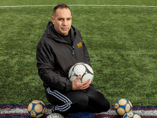 Coach David Dikranian sitting in the center of a soccer field