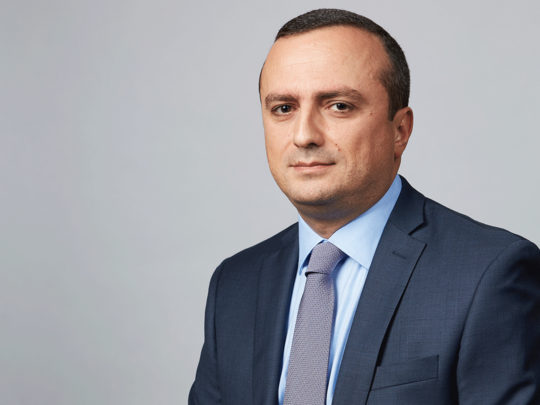 Robert Avetisyan, poses for a photographer in a blue suit and purple tie.