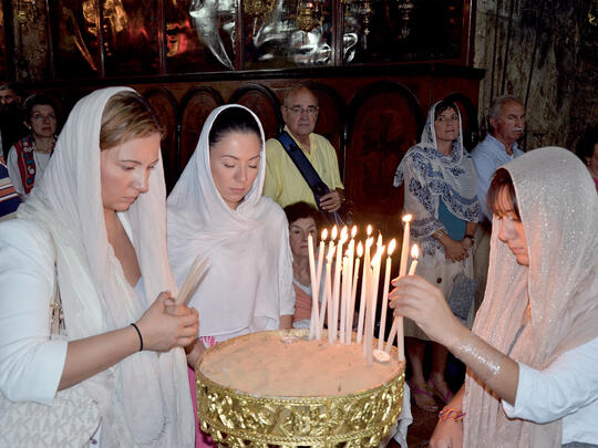 Three sisters on a pilgrimage organized by the St. James Armenian Church of Watertown, MA light candles in the Tomb of the Virgin Mary in Gethsemane.