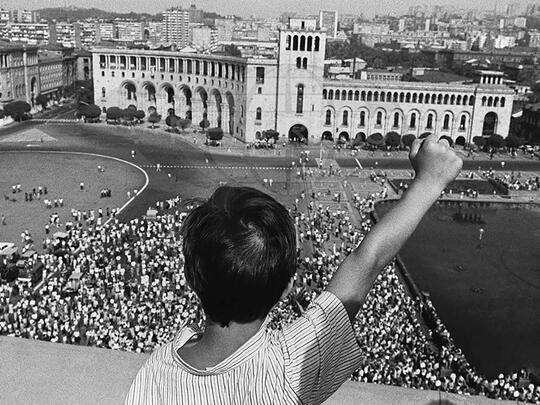 An Armenian youth raises his Karabakh Movement-inspired fist from the balcony of the Government building as a sign of its nascent independence.