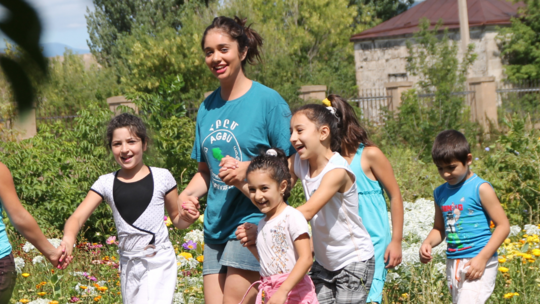 Discover Armenia participant holding children's hands in a field in Armenia